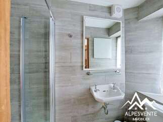 This modern bathroom features a sleek design with gray tiled walls and a glass shower enclosure.