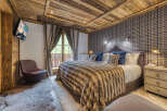 Experience luxury in this exquisite bedroom featuring a cozy, fur-like blanket and a plush, upholstered headboard.