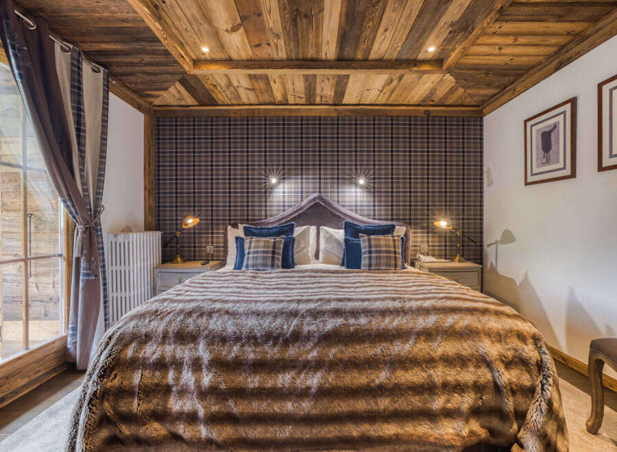 Experience rustic charm in this cozy bedroom, featuring a luxurious faux fur throw blanket and a striking plaid headboard.
