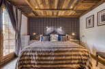 Experience rustic charm in this cozy bedroom, featuring a luxurious faux fur throw blanket and a striking plaid headboard.