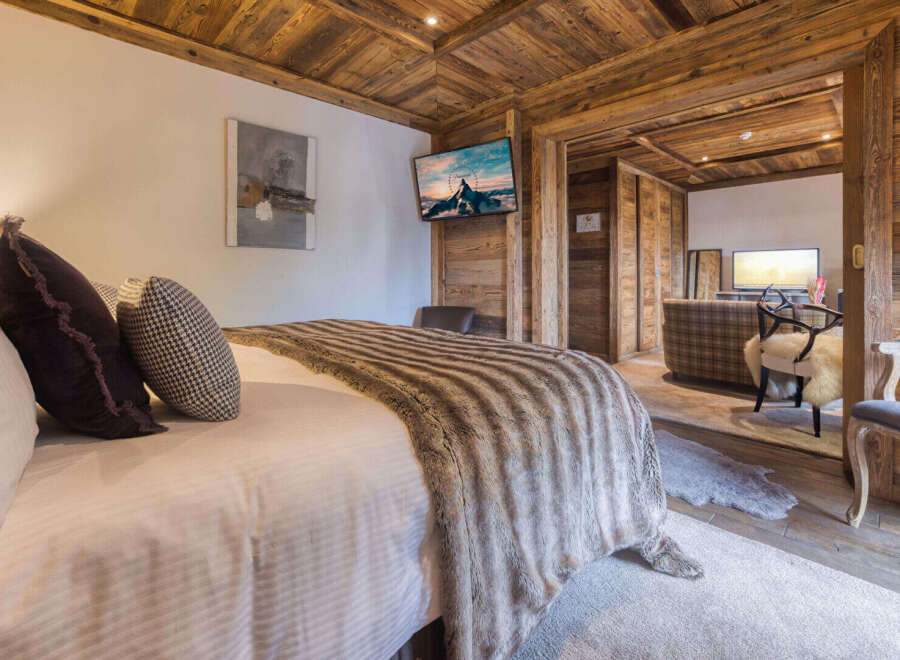 Experience rustic luxury in this charming bedroom, featuring a plush bed adorned with a cozy faux fur throw and decorative pillows.