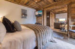 Experience rustic luxury in this charming bedroom, featuring a plush bed adorned with a cozy faux fur throw and decorative pillows.