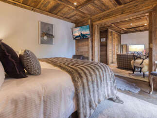 Experience rustic luxury in this charming bedroom, featuring a plush bed adorned with a cozy faux fur throw and decorative pillows.