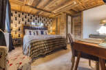 Experience rustic charm in this beautifully appointed bedroom, featuring a luxurious king-size bed with a plush fur throw and a striking deer-themed wallpaper.