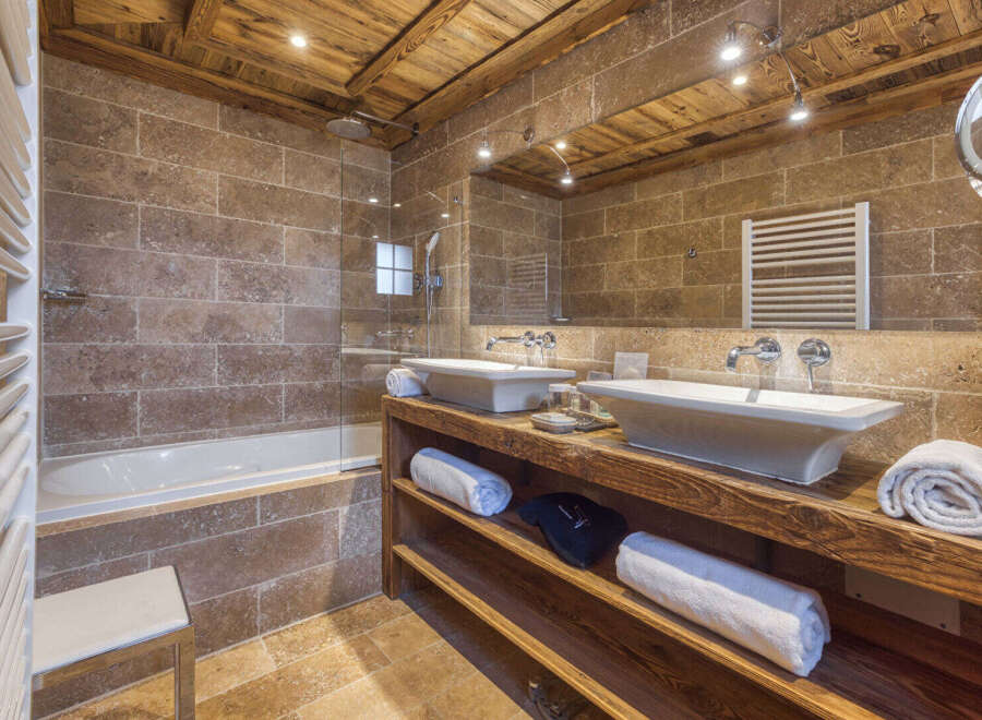 Experience rustic luxury in this stunning bathroom, featuring a deep soaking tub and a spacious walk-in shower with travertine tile accents.
