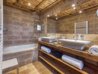 Experience rustic luxury in this stunning bathroom, featuring a deep soaking tub and a spacious walk-in shower with travertine tile accents.