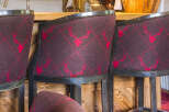 Experience rustic elegance in this charming bar area, featuring plush bar stools upholstered in a rich, dark fabric with a distinctive red stag pattern.