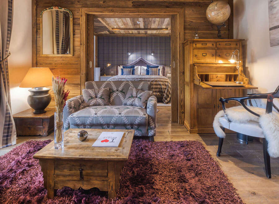 Experience rustic luxury in this charming alpine suite, featuring a cozy living area with a patterned sofa and a rustic wooden coffee table.