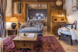 Experience rustic luxury in this charming alpine suite, featuring a cozy living area with a patterned sofa and a rustic wooden coffee table.