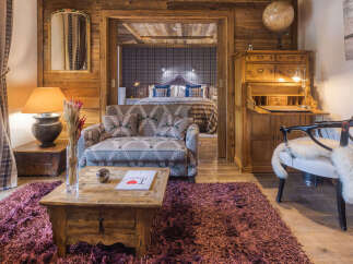 Experience rustic luxury in this charming alpine suite, featuring a cozy living area with a patterned sofa and a rustic wooden coffee table.