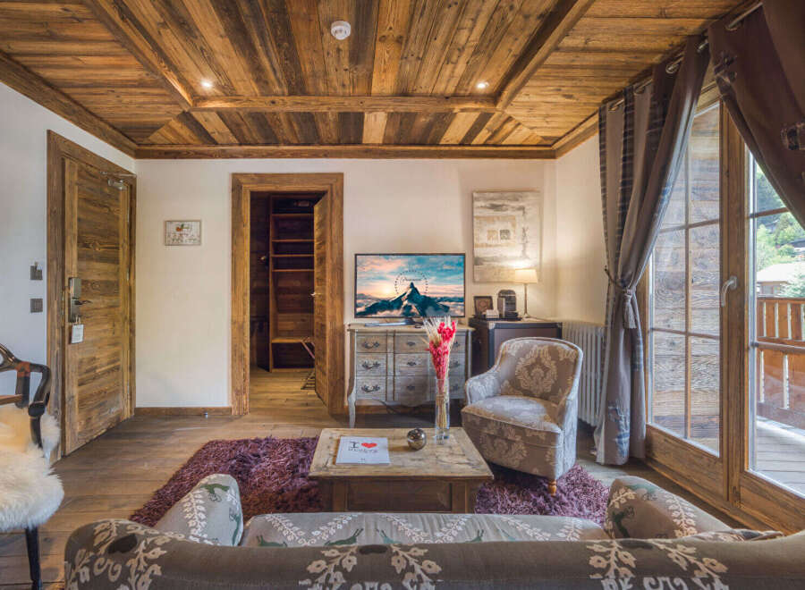 Experience rustic charm in this beautifully appointed living room, featuring a stunning wood-paneled ceiling and walls that exude warmth and alpine elegance.