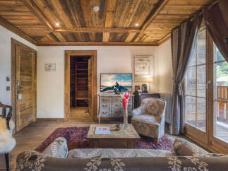 Experience rustic charm in this beautifully appointed living room, featuring a stunning wood-paneled ceiling and walls that exude warmth and alpine elegance.