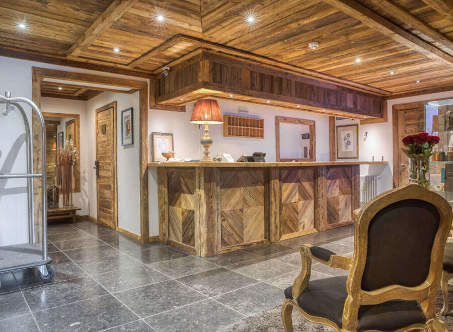 Experience rustic charm in this hotel lobby, featuring a stunning wooden reception desk with intricate geometric patterns.