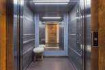 Step into this luxurious elevator, featuring a modern design with dark wood-paneled walls and sleek stainless steel accents.