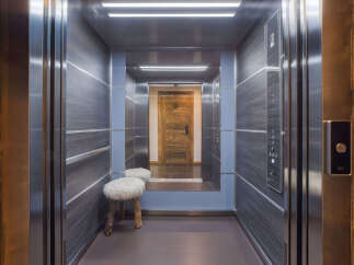Step into this luxurious elevator, featuring a modern design with dark wood-paneled walls and sleek stainless steel accents.