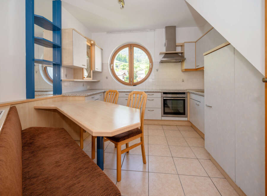 This charming kitchen features a unique design with a round window offering scenic views.