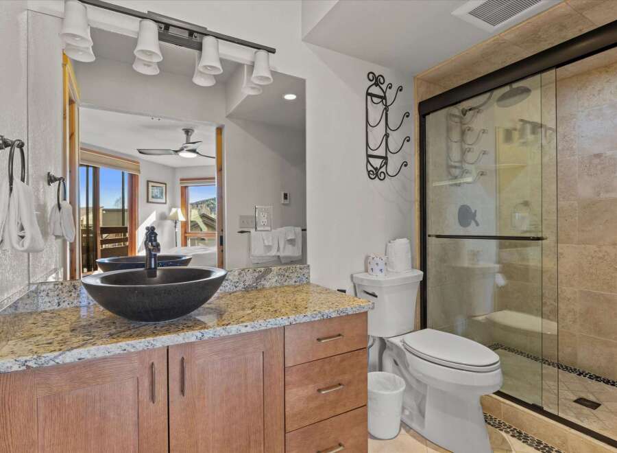 This luxurious bathroom features a stunning granite countertop and a stylish black vessel sink, creating a sophisticated and modern aesthetic.