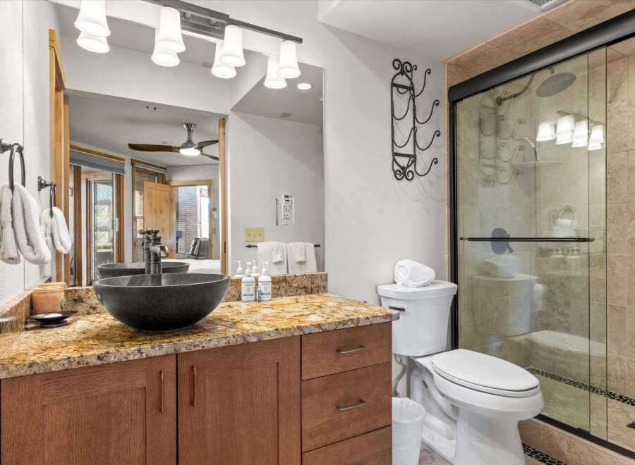 Step into luxury with this stunning bathroom featuring a sleek black vessel sink and a beautiful granite countertop.