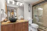 Step into luxury with this stunning bathroom featuring a sleek black vessel sink and a beautiful granite countertop.