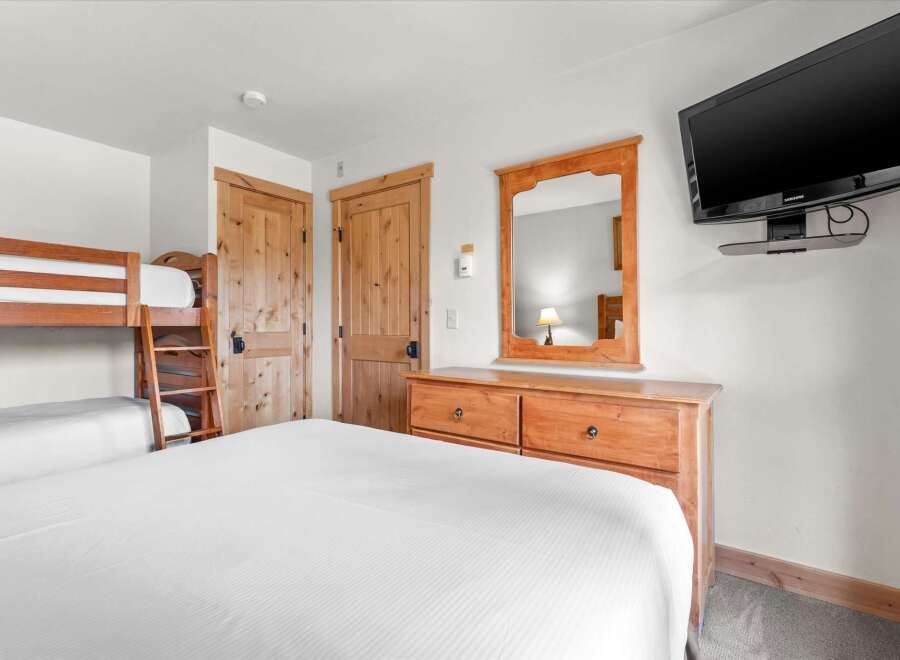 This cozy bedroom features a comfortable bed and a set of bunk beds, perfect for families or groups.