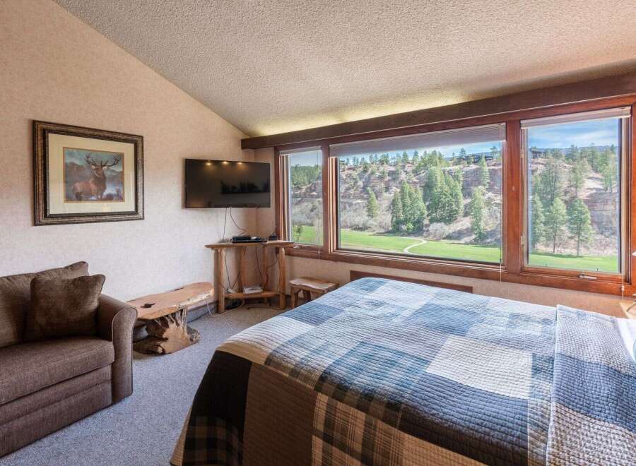 Experience the tranquility of this stunning bedroom, featuring a picturesque view of a lush green landscape.
