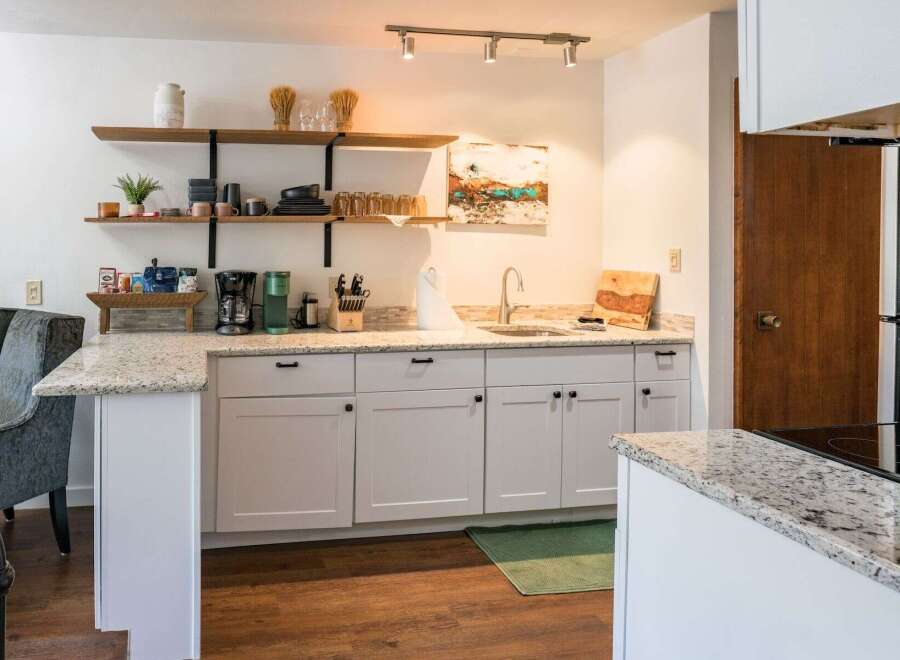This stunning kitchen boasts a modern design with sleek white cabinetry and granite countertops, creating a bright and inviting space.