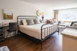 Discover the charm of this inviting bedroom, featuring a stylish wrought iron bed and a cozy ambiance.