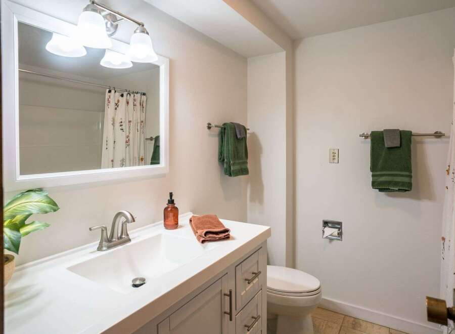 This bathroom features a bright and airy design with a modern vanity and a large mirror.