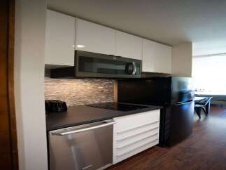 Discover modern living in this stylish studio apartment! The kitchen boasts sleek, white cabinetry, a stainless steel dishwasher, and a built-in microwave, perfect for effortless meal prep.