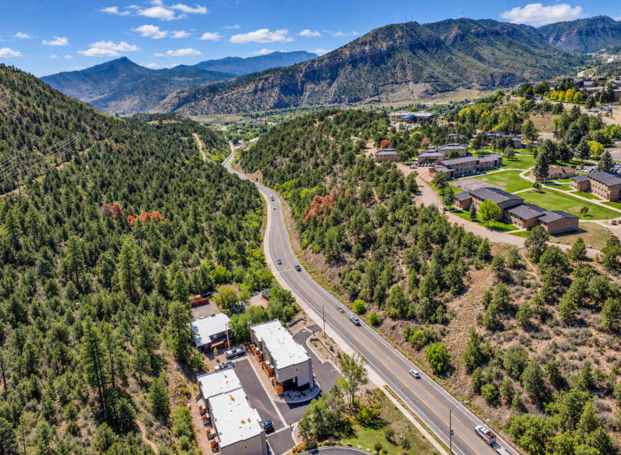 Discover this stunning aerial view showcasing a modern residential complex nestled amidst a picturesque mountain landscape.