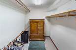 Step into this spacious walk-in closet, offering ample storage with its built-in shelving and a classic wooden dresser.