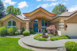 Welcome to this stunning home featuring a striking teal front door and a charming tiered fountain in the landscaped front yard.