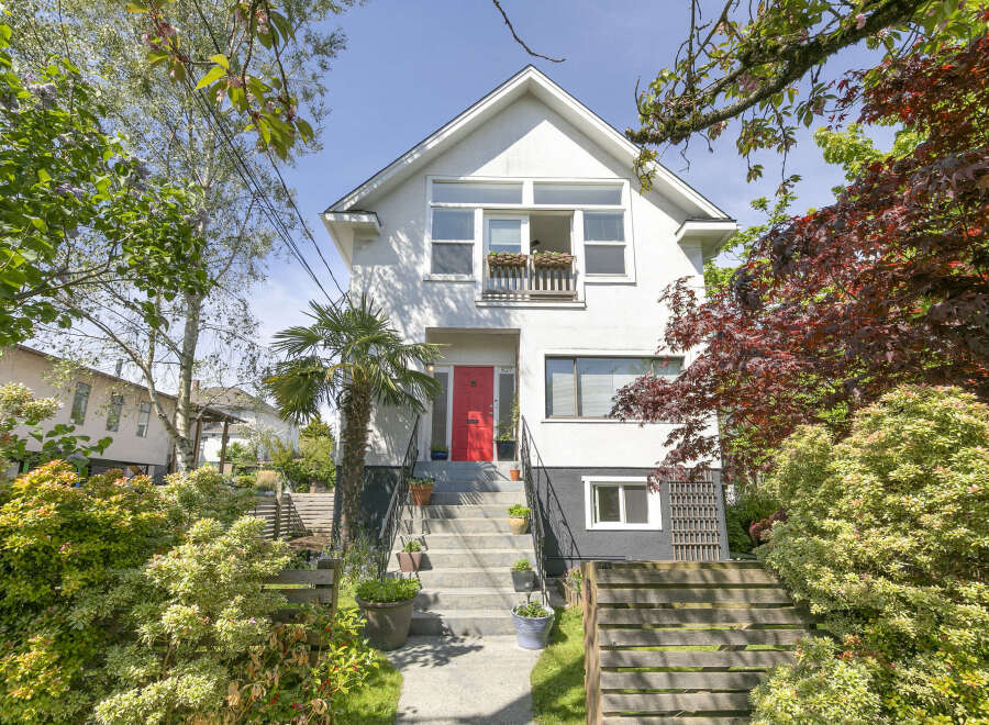 Charming two-story home with a vibrant red front door, offering a welcoming entrance.