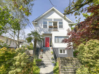 Charming two-story home with a vibrant red front door, offering a welcoming entrance.