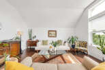 This stunning living room boasts a bright and airy atmosphere with its vaulted ceilings and ample natural light.