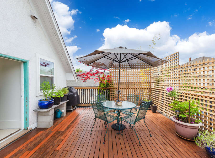 Enjoy outdoor living at its finest on this beautiful deck! Featuring a charming patio set, lush greenery, and a stylish umbrella, this space is perfect for relaxation and entertaining.