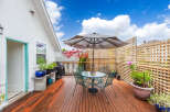 Enjoy outdoor living at its finest on this beautiful deck! Featuring a charming patio set, lush greenery, and a stylish umbrella, this space is perfect for relaxation and entertaining.