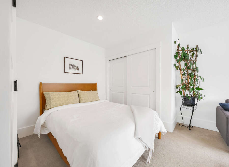 This cozy bedroom offers a serene retreat with its bright, white walls and ample natural light.