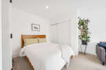 This cozy bedroom offers a serene retreat with its bright, white walls and ample natural light.