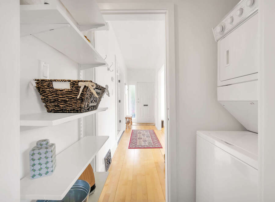 This bright and airy laundry room features a stacked washer and dryer, maximizing space and efficiency.