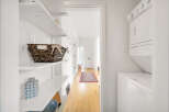 This bright and airy laundry room features a stacked washer and dryer, maximizing space and efficiency.