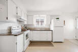This bright and airy kitchen features white cabinetry, offering a clean and modern aesthetic.