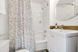 This bright bathroom features a clean, modern design with a white vanity and a stylish, floral-patterned shower curtain.
