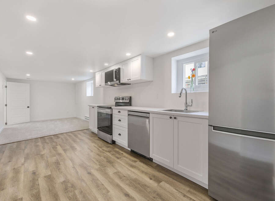 This stunning kitchen boasts modern appliances and sleek white cabinetry, perfect for culinary enthusiasts.
