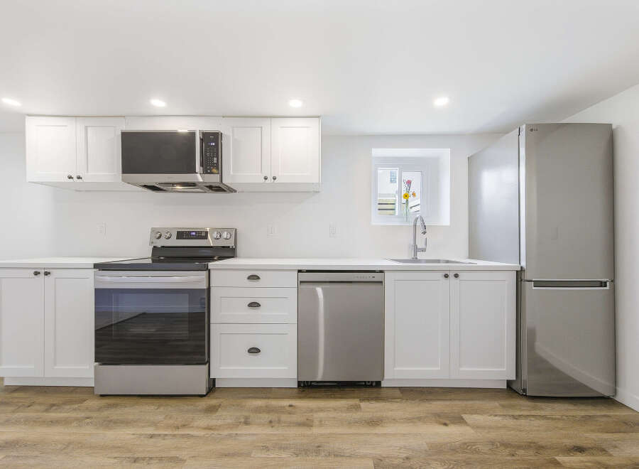 This modern kitchen boasts sleek white cabinetry, stainless steel appliances, and a stylish design.