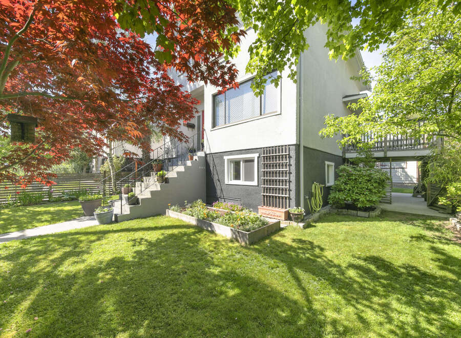 This charming property boasts a beautifully landscaped front yard with lush green grass and vibrant flower beds.