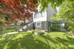 This charming property boasts a beautifully landscaped front yard with lush green grass and vibrant flower beds.