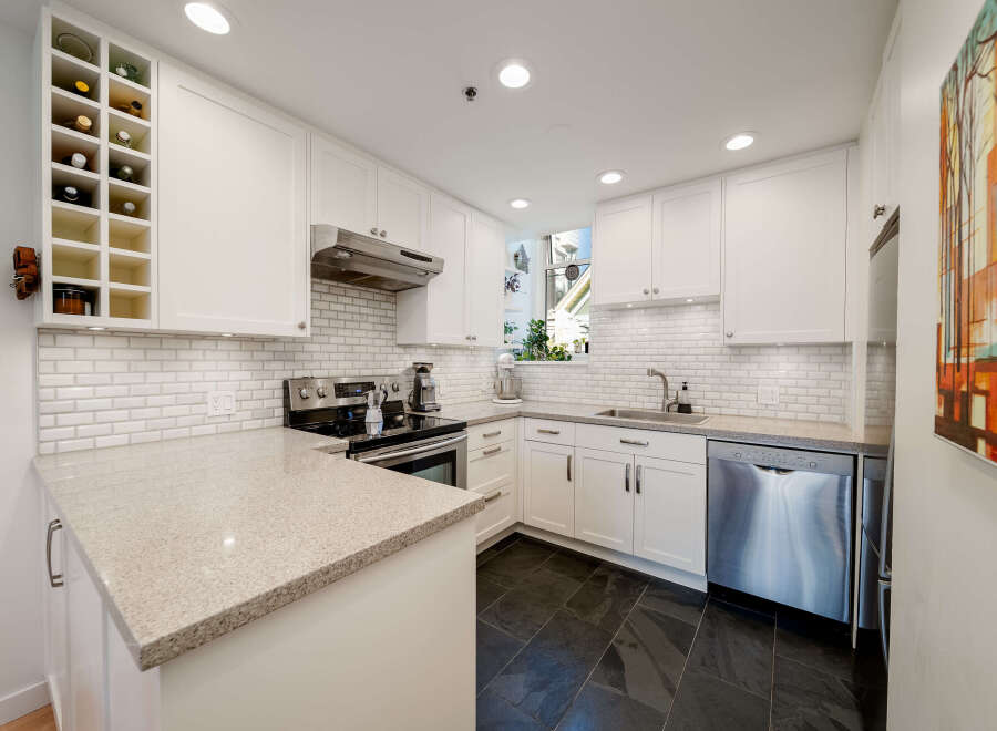 This stunning kitchen boasts a modern design with sleek white cabinetry and a beautiful granite countertop.