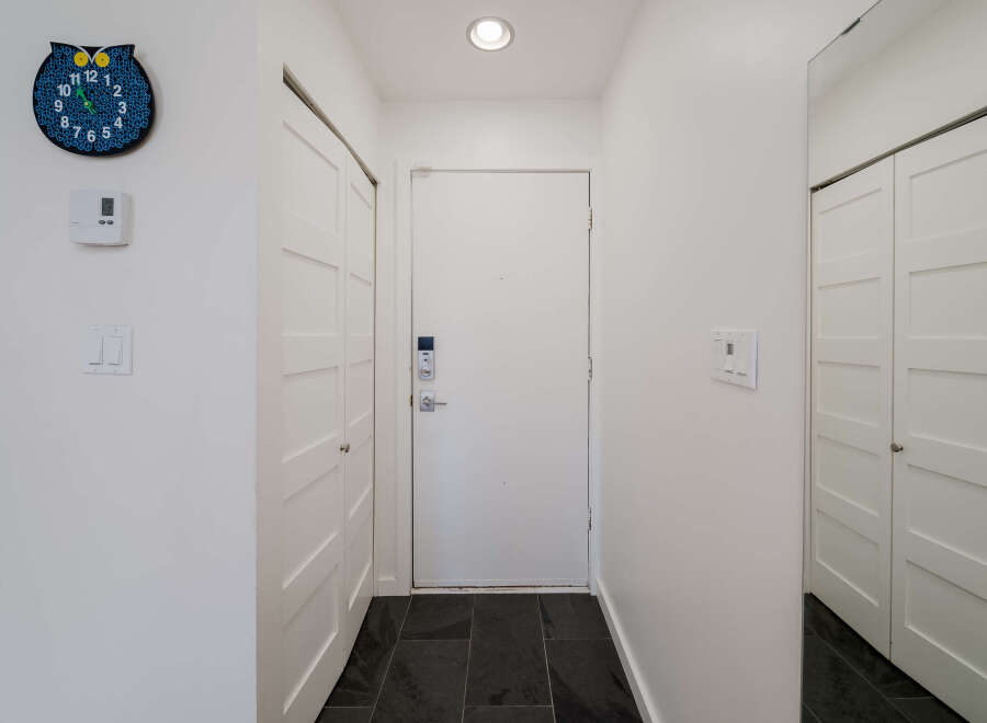 Step into this inviting entryway, featuring a stylish owl clock and modern white doors.