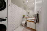 This well-appointed bathroom features a modern design with a convenient stacked washer and dryer.